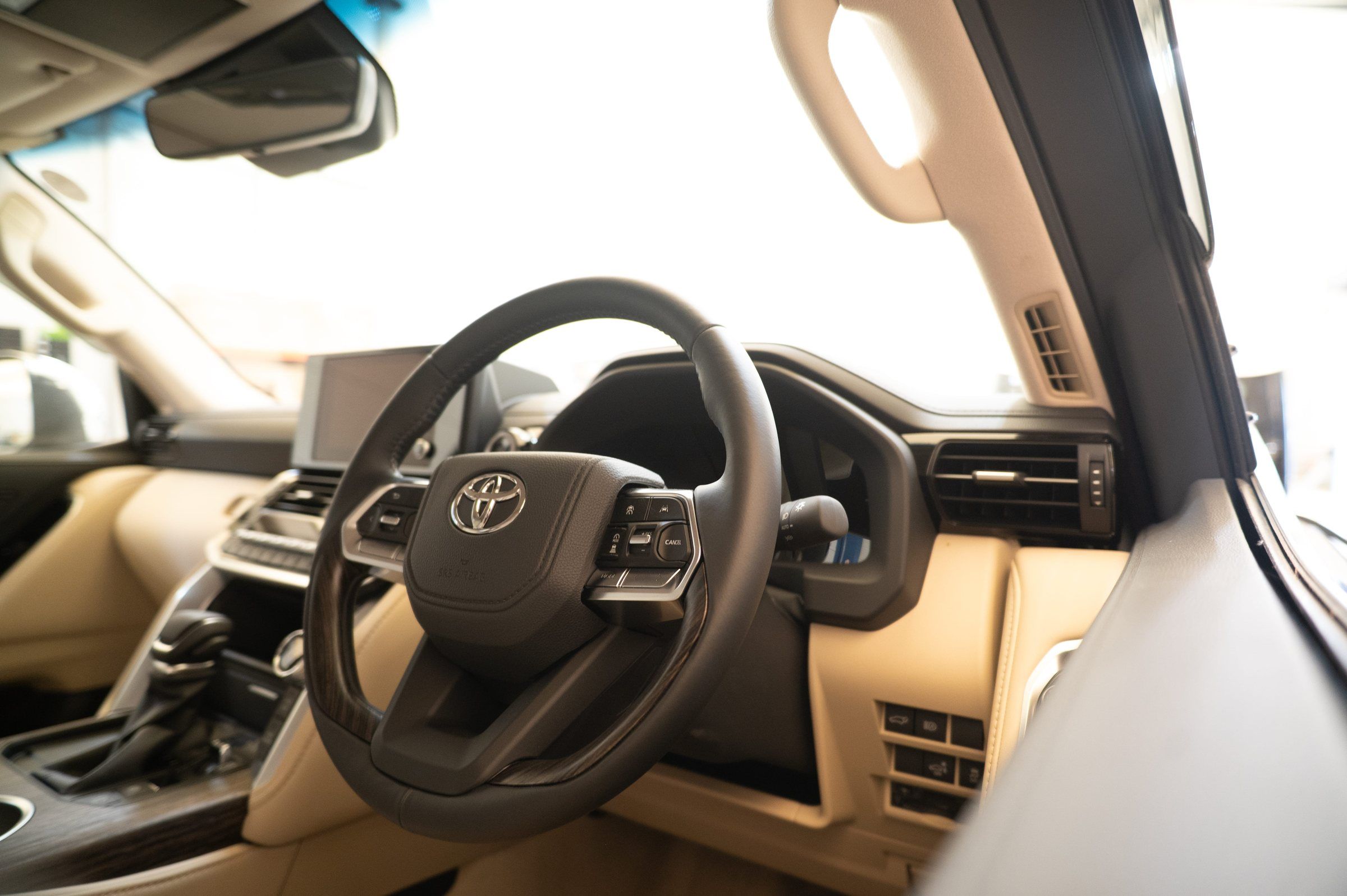 The cream leather interior and right-hand-drive steering wheel of a Toyota Alphard