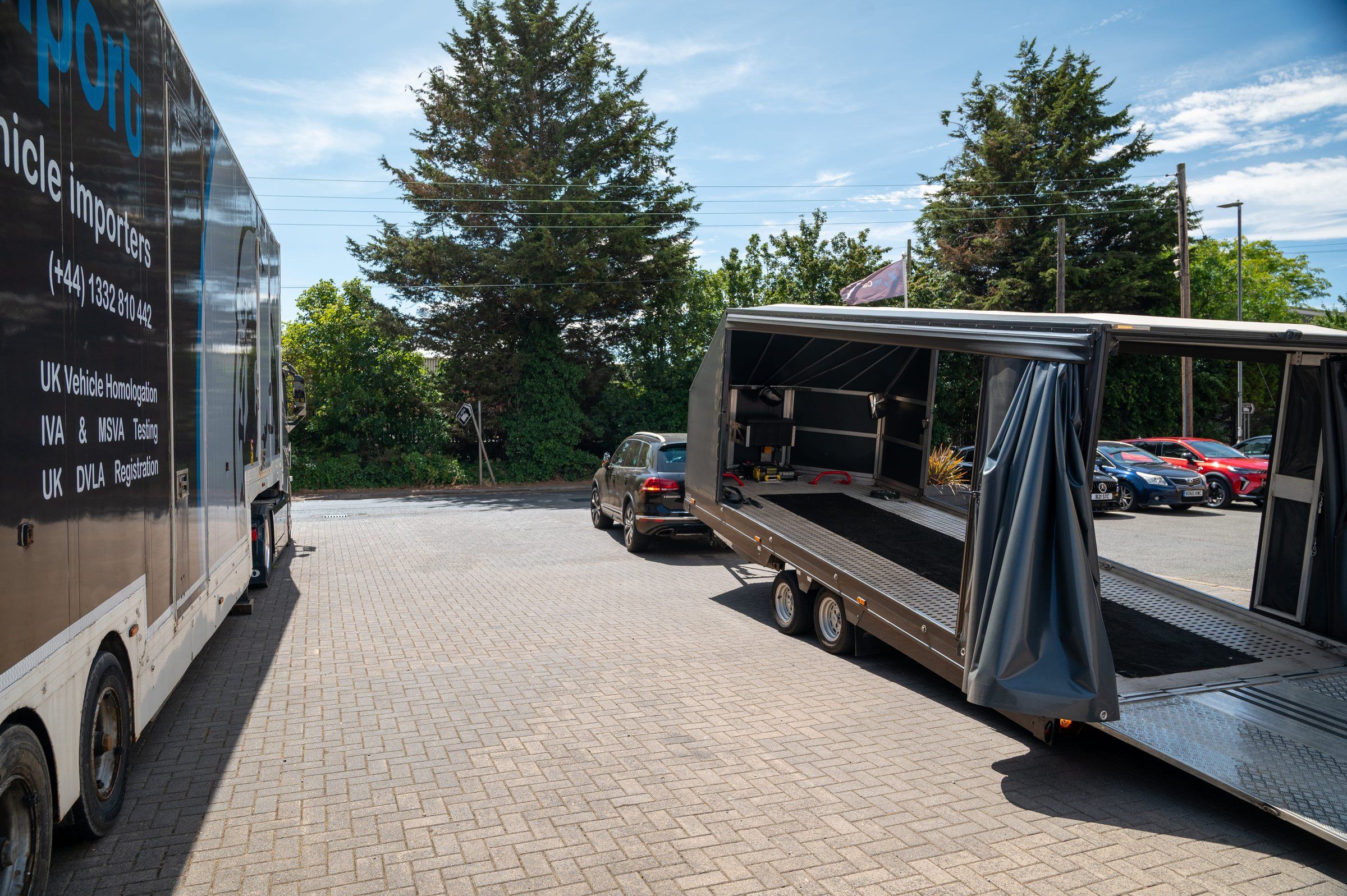 A My Car Import branded enclosed car transporter on the forecourt, its rear ramp lowered