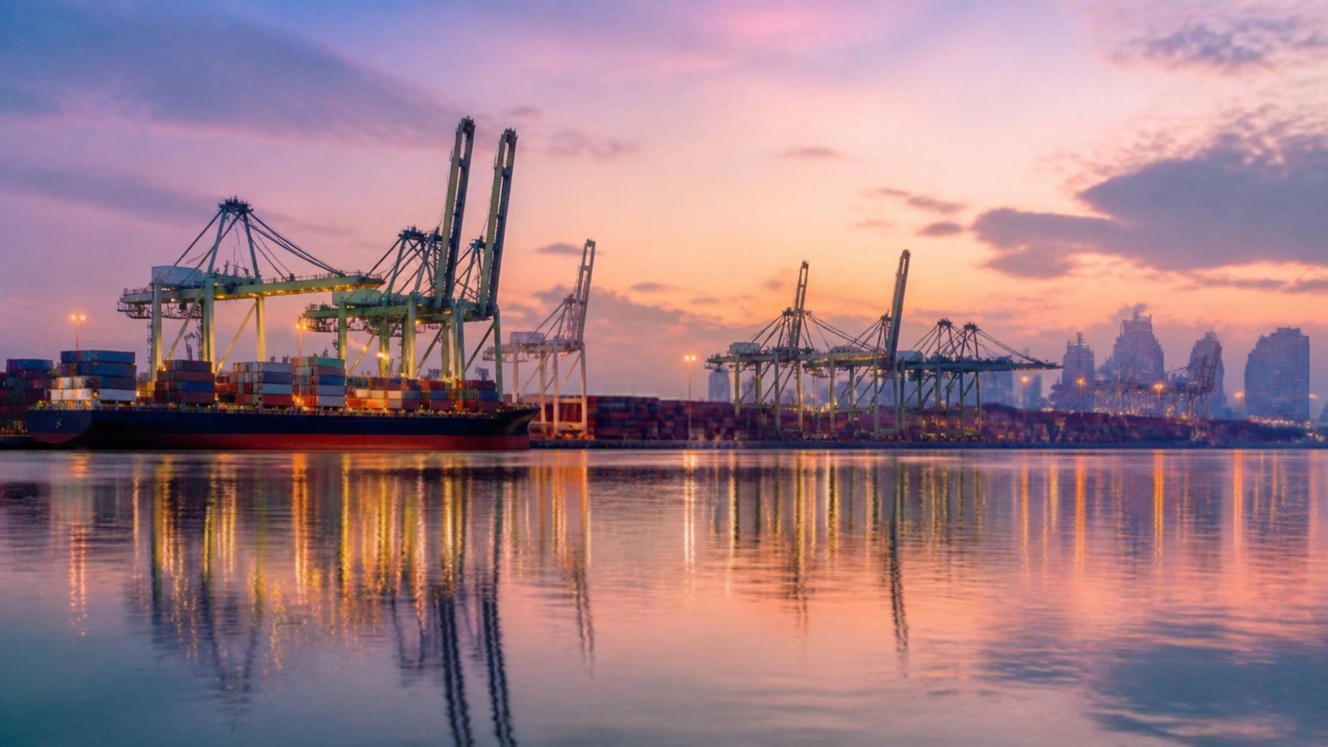 Gantry cranes and stacked containers at a Singapore container port at dawn